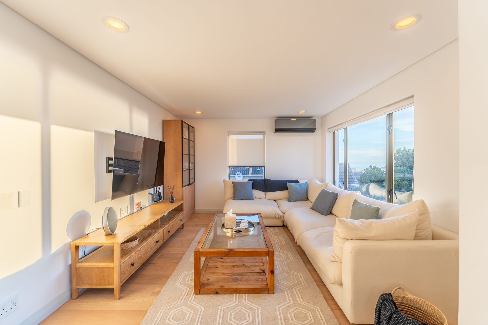Living room with a cream corner sofa, glass coffee table and wall-mounted television